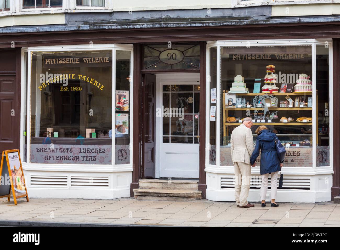 Couple âgé regardant dans la fenêtre de la Patisserie Valerie est 1926 à Oxford, Oxfordshire Royaume-Uni lors d'une journée humide de pluie en août Banque D'Images