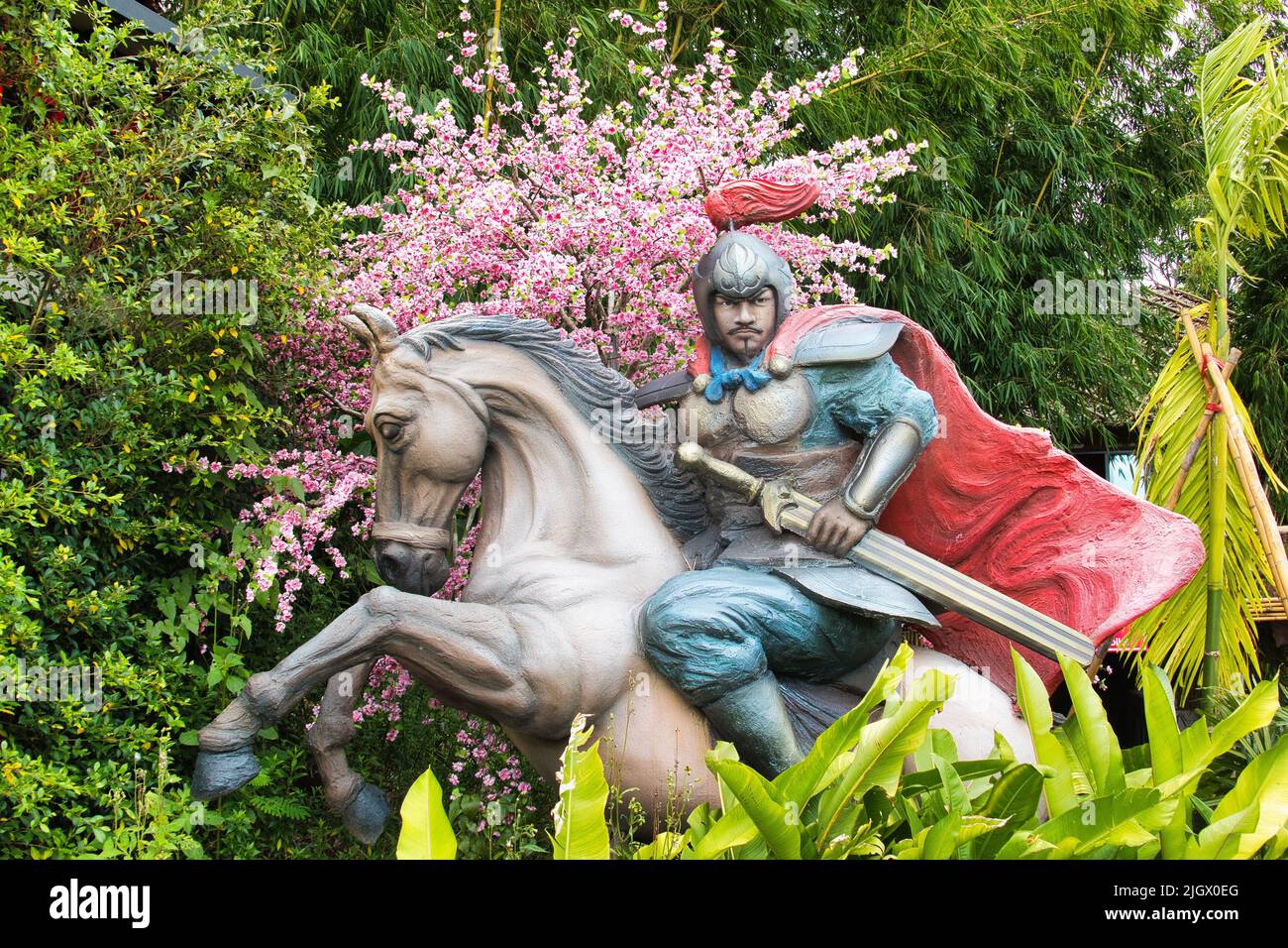 Statue peinte d'un guerrier à cheval, au complexe Liangshan Khaokho à Khao Kho, Phetchabun, Thaïlande, sur fond de cerisiers en fleurs. Banque D'Images