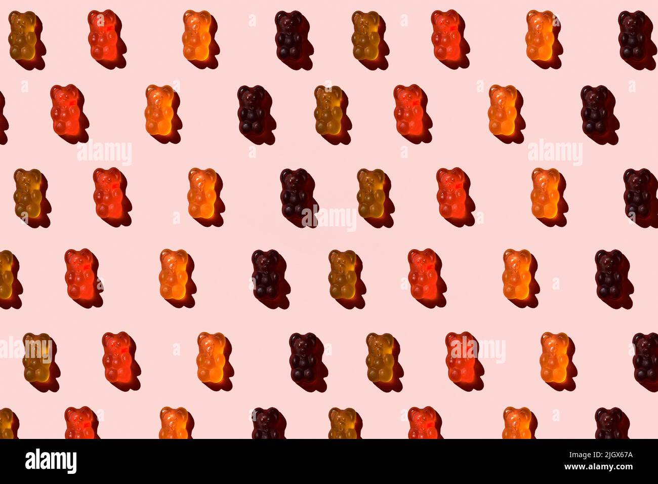 Motif composé d'ours en gelée colorés sur fond rose. Pose à plat. Concept minimal Banque D'Images