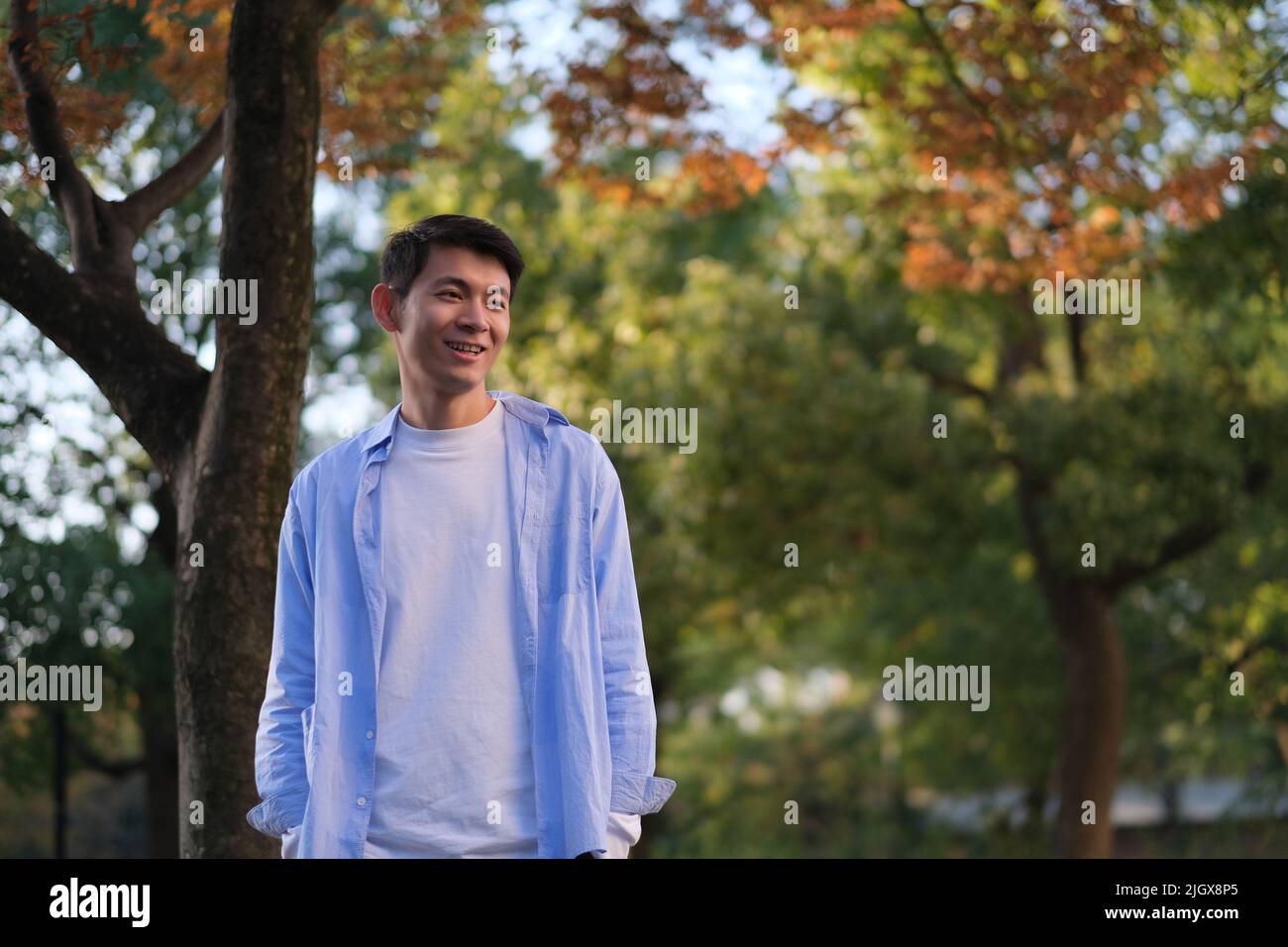 Souriant beau jeune asiatique en forêt en automne Banque D'Images