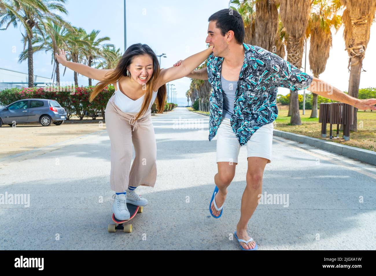 Jeune couple diversifié avec skateboard et longue planche à roulettes s'amuser en plein air. Banque D'Images