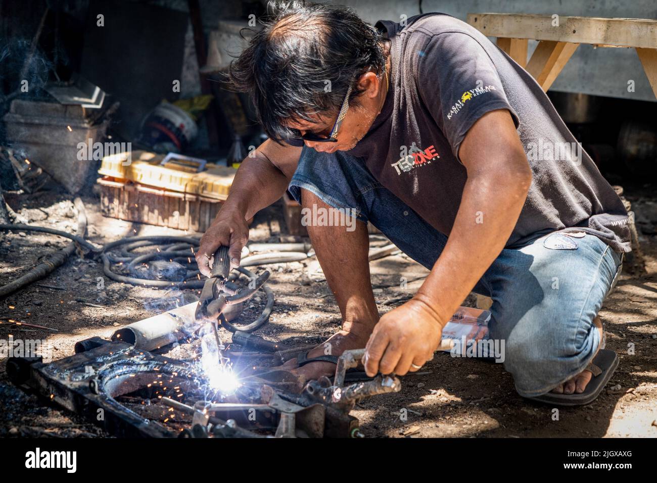 Un mécanicien soud une pièce ensemble pour une moto 'trike' (tricycle), l'une des formes de transport les plus courantes et abordables aux Philippines. La vie quotidienne dans le district de Moalboal, Cebu, Philippines. La région autrefois connue pour sa plongée sous-marine et ses immenses nuages de sardines a eu du mal à raviver le tourisme, même après avoir levé les restrictions de voyage de Covid-19 en raison des dommages d'infrastructure critiques causés par le typhon Rai, également connu sous le nom de Super Typhoon Odette, qui a laissé une grande partie de la région décimée et lutté pour la reconstruction. Banque D'Images