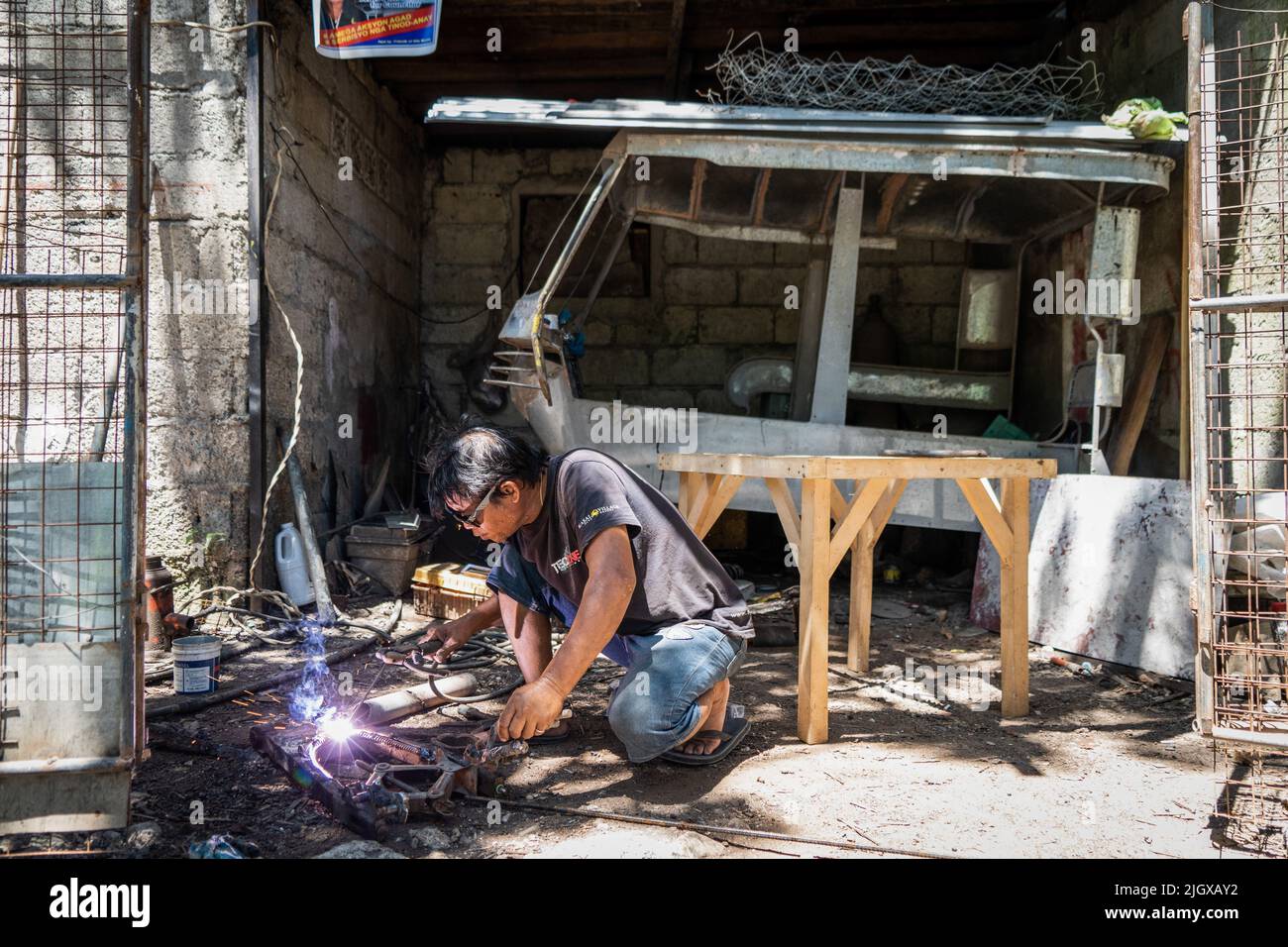 Un mécanicien soud une pièce ensemble pour une moto 'trike' (tricycle), l'une des formes de transport les plus courantes et abordables aux Philippines. La vie quotidienne dans le district de Moalboal, Cebu, Philippines. La région autrefois connue pour sa plongée sous-marine et ses immenses nuages de sardines a eu du mal à raviver le tourisme, même après avoir levé les restrictions de voyage de Covid-19 en raison des dommages d'infrastructure critiques causés par le typhon Rai, également connu sous le nom de Super Typhoon Odette, qui a laissé une grande partie de la région décimée et lutté pour la reconstruction. Banque D'Images