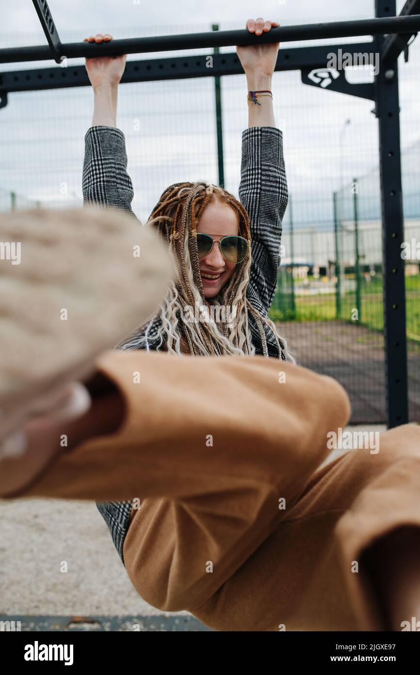 Jeune fille adolescente avec des bandes accrochées à un bar haut, la frapper à sa botte l'appareil photo. Sourire, porter des lunettes de soleil. Banque D'Images