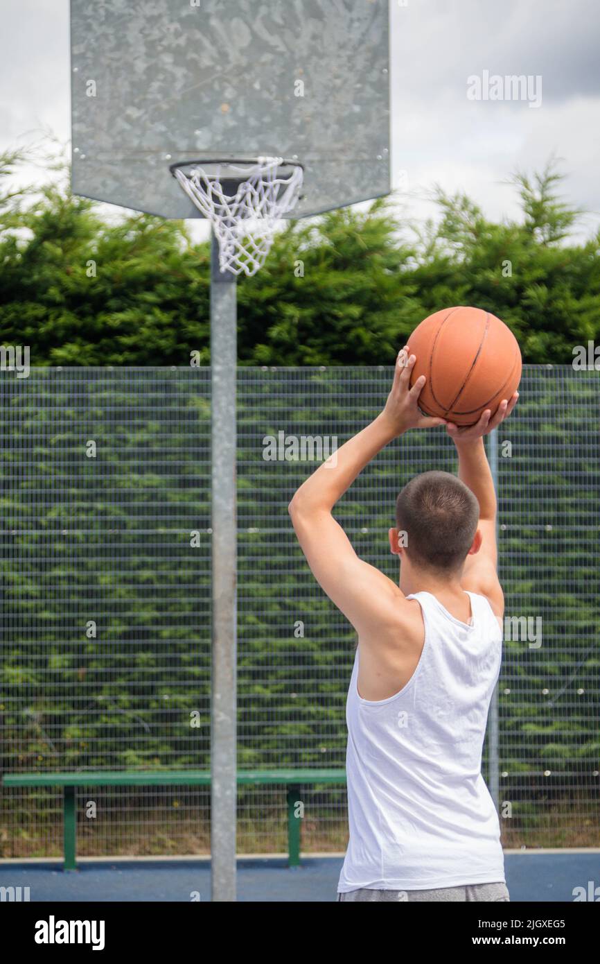Un adolescent de Nineteen a tiré un Hoop sur Un terrain de basket-ball dans Un parc public Banque D'Images