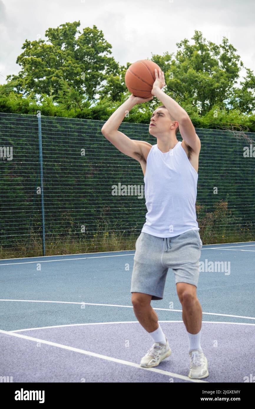 Un adolescent de Nineteen a tiré un Hoop sur Un terrain de basket-ball dans Un parc public Banque D'Images
