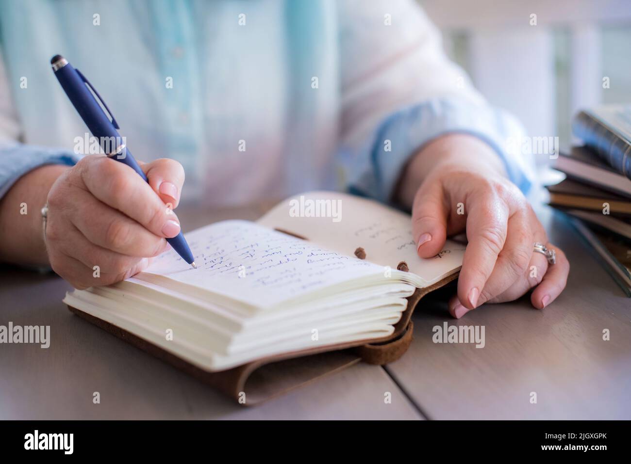Gros plan des mains de la femme blanche écrivant dans un journal Banque D'Images