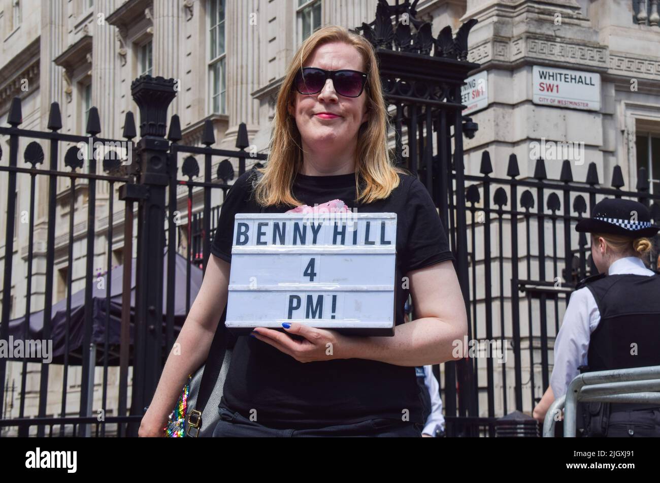 Londres, Royaume-Uni. 13th juillet 2022. Un manifestant à l'extérieur de Downing Street tient un panneau faisant référence à la demande de l'acteur Hugh Grant de jouer le thème du Benny Hill Show. Des manifestants anti-conservateurs et anti-Boris Johnson se sont rassemblés à Westminster alors que Johnson devait faire face aux questions de son premier Premier ministre depuis sa démission. Les manifestants ont exigé qu'il quitte son poste immédiatement.Credit: Vuk Valcic/Alamy Live News Banque D'Images