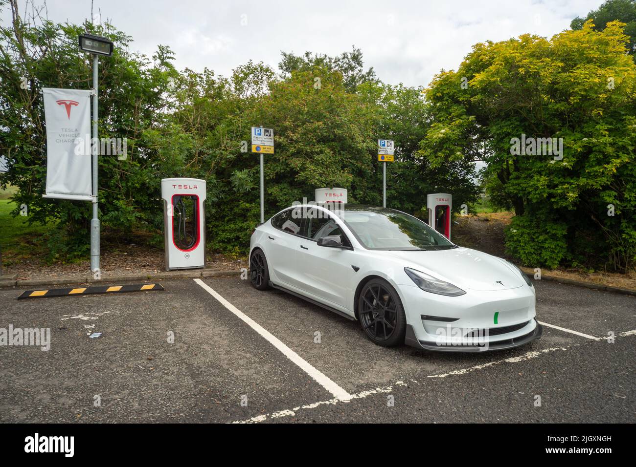 Point de charge du Supercharger Tesla avec voiture Tesla garée, Welcome Break Services Abington, Écosse, Royaume-Uni Banque D'Images