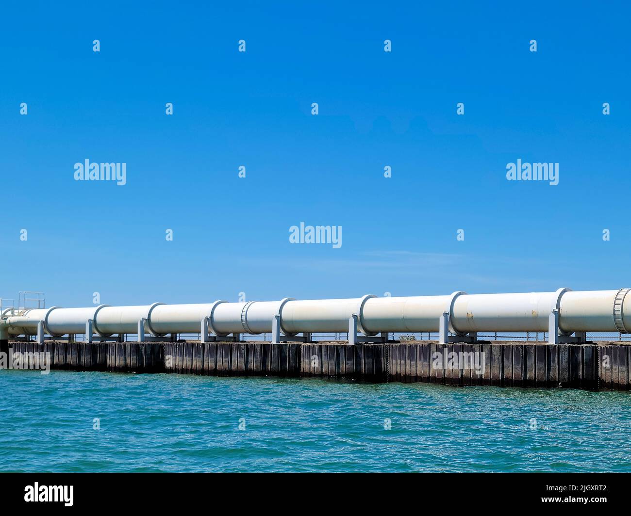 Pipeline blanc industriel sur le lac Michigan avec ciel bleu vif Banque D'Images Pipeline blanc industriel sur le lac Michigan avec ciel bleu vif Banque D'Images