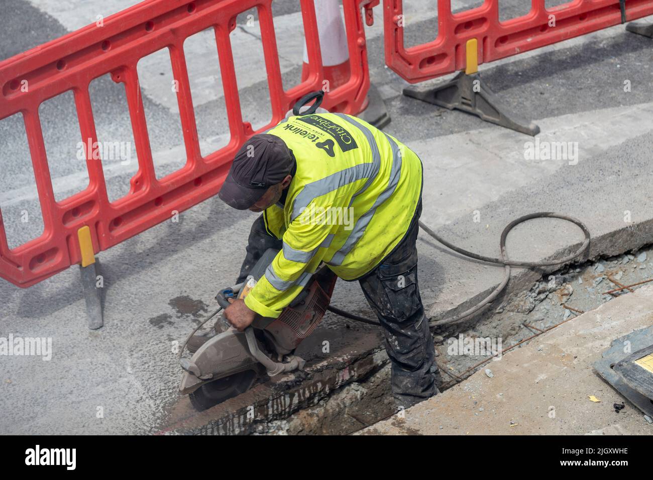 Le réseau fibre intégrale CityFiber est installé dans la zone Southend on Sea pour le haut débit. Travaux de terrain en cours sur la route résidentielle. Travailleur utilisant une scie à pierre Banque D'Images