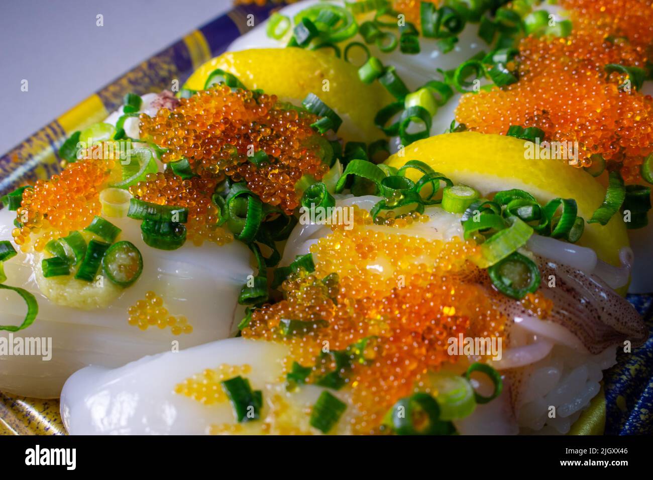 Une garniture Ika Sushi (Squid Sushi) à emporter avec du tobiko (Tobikko, œuf de poisson volante) et un oignon vert haché sur un plateau Banque D'Images