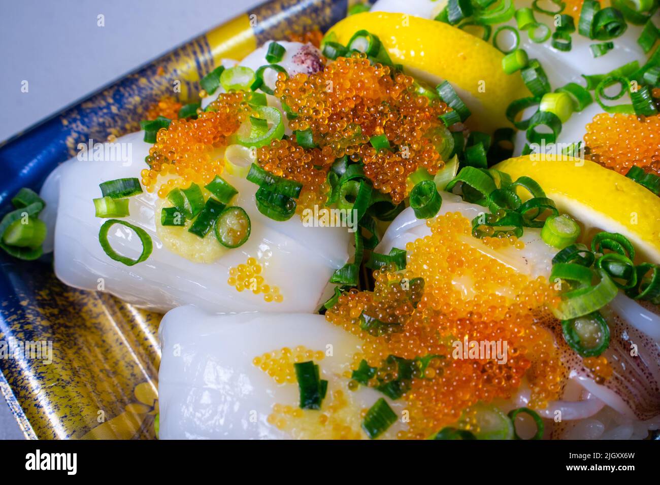 Une garniture Ika Sushi (Squid Sushi) à emporter avec du tobiko (Tobikko, œuf de poisson volante) et un oignon vert haché sur un plateau Banque D'Images