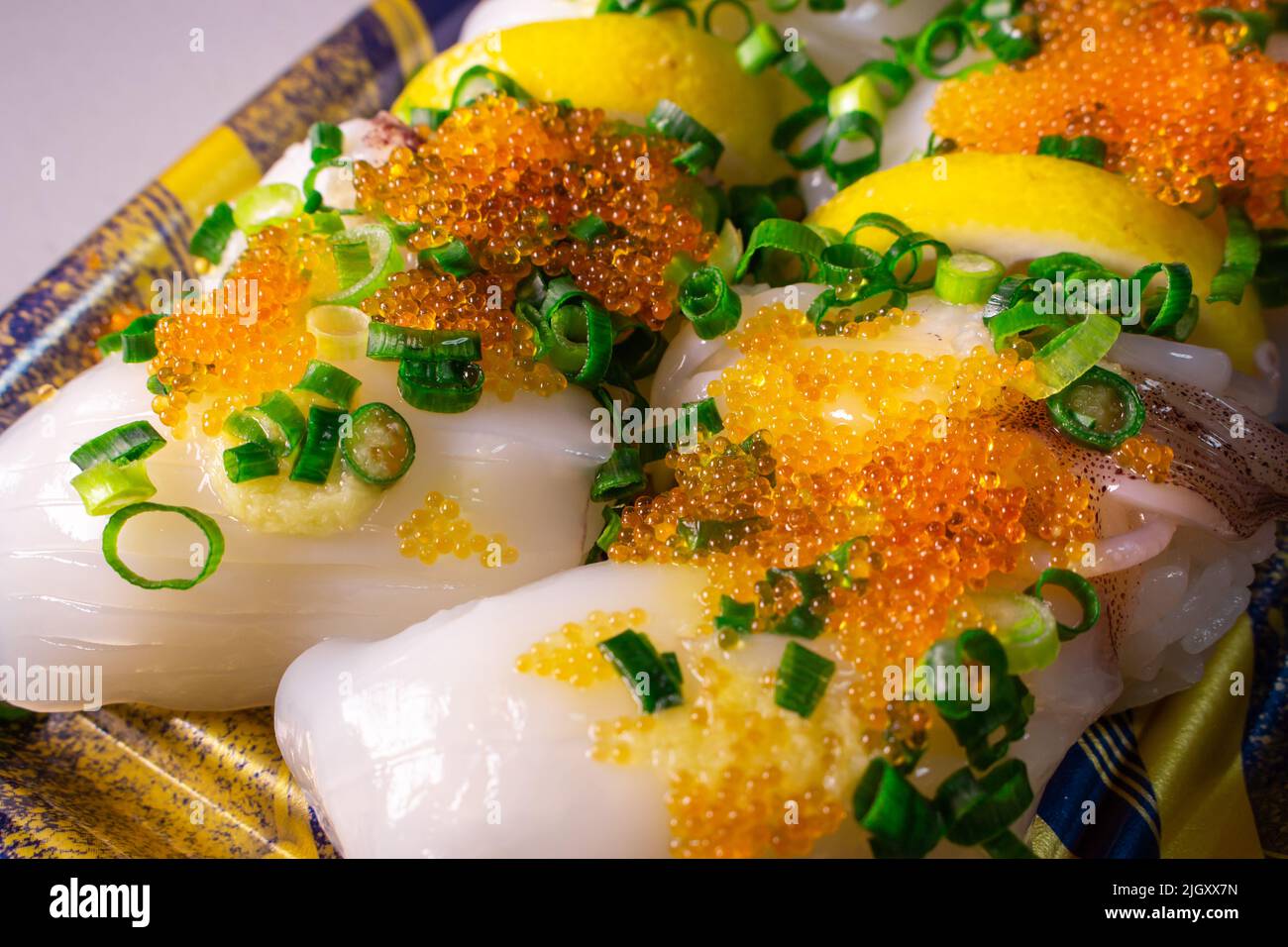Une garniture Ika Sushi (Squid Sushi) à emporter avec du tobiko (Tobikko, œuf de poisson volante) et un oignon vert haché sur un plateau Banque D'Images