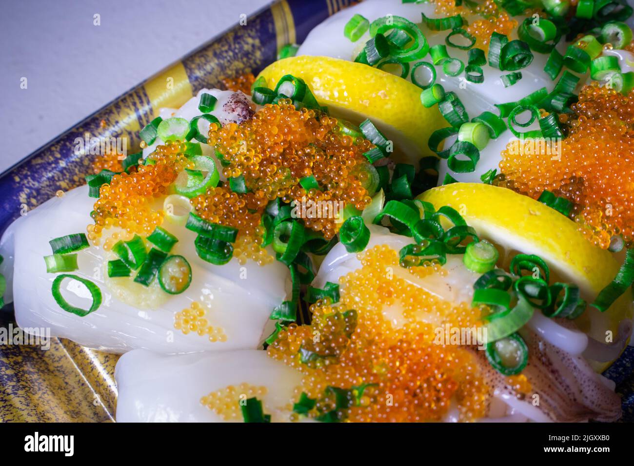 Une garniture Ika Sushi (Squid Sushi) à emporter avec du tobiko (Tobikko, œuf de poisson volante) et un oignon vert haché sur un plateau Banque D'Images