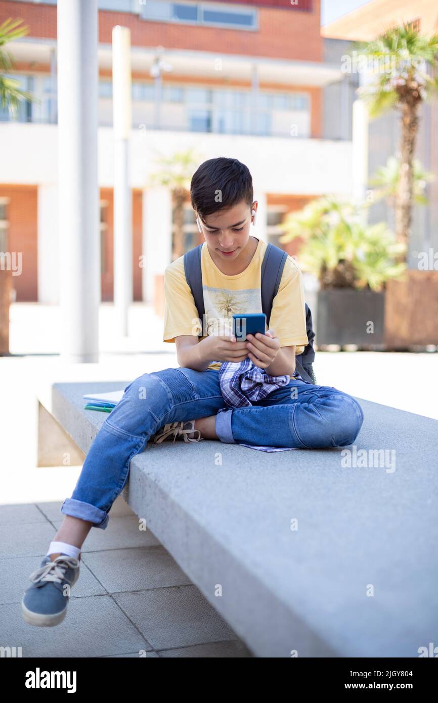 Un jeune étudiant de lycée du Caucase utilisant un téléphone portable à l'extérieur. Espace pour le texte. Banque D'Images