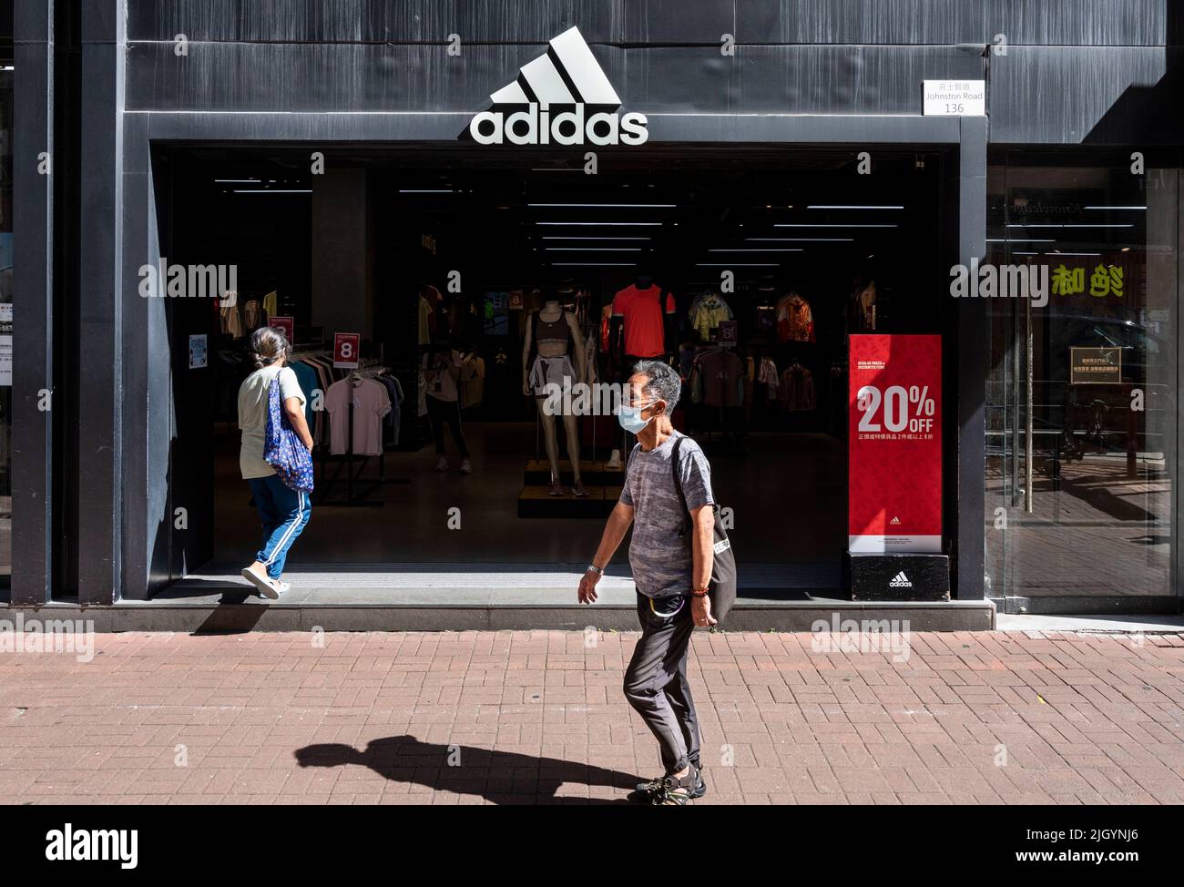 Des piétons marchent devant le magasin Adidas de la marque multinationale allemande de vêtements de sport à Hong Kong. Banque D'Images