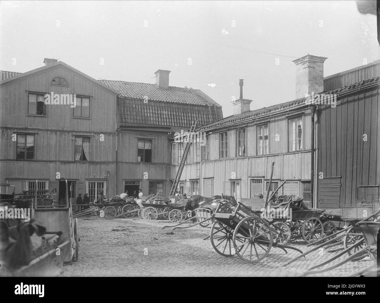 Intérieur de la ferme, Svartbäcksgatan 23, quartier de Hjorten, Dragarbrunn, Uppsala 1908. Svartbäcksgatan 23 dans le bloc Hjorten. Une ferme commerciale caractéristique dont les bâtiments proviennent principalement du 1820s. La ferme était l'un des nombreux quartiers fermiers le long de Svartbäcksgatan. La cour servait de stand aux chevaux et aux cavaliers des clients. Pendant les marchés, vous pourriez à la fois compter jusqu'à 80 chevaux et 20 agriculteurs qui ont passé la nuit dans les soi-disant Bodkamers de la ferme. 'D'Ola Ehn & Gunnar Elfström, le tournant du siècle Uppsala dans les images de Dahlgren. Nature et culture 1977. Banque D'Images