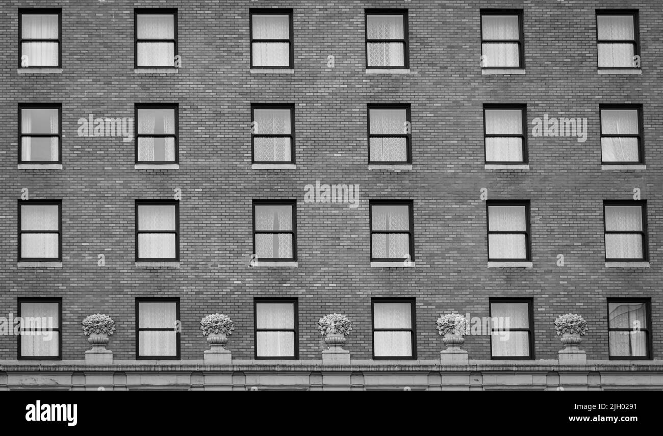 De nombreuses fenêtres en rangée sur la façade de l'immeuble urbain. Bâtiment en briques. Photo de rue, personne, mise au point sélective Banque D'Images
