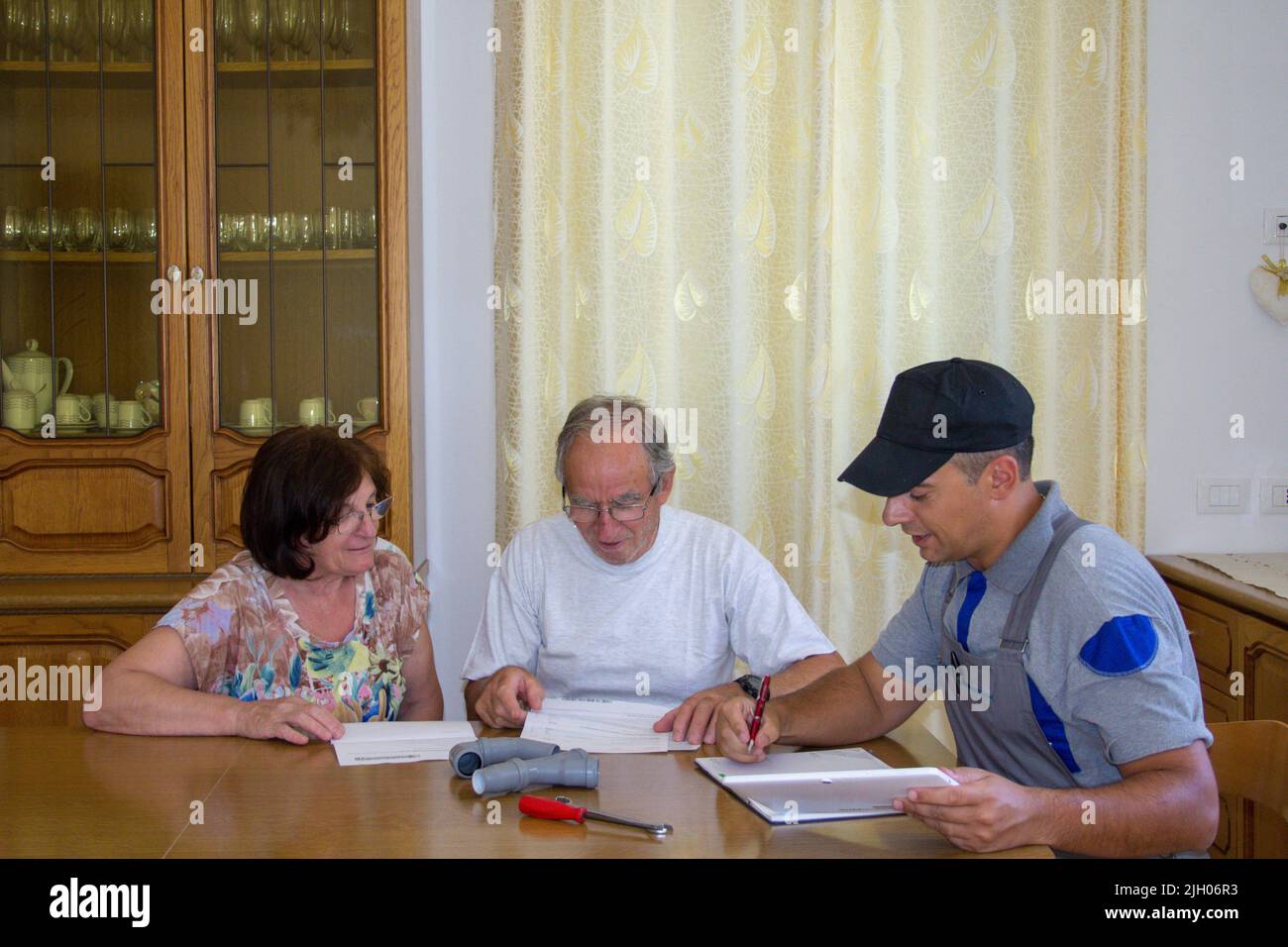 Image d'un plombier de handyman expliquant à un couple âgé le travail de réparation et l'estimation du travail à faire à la maison en les faisant signer le Banque D'Images