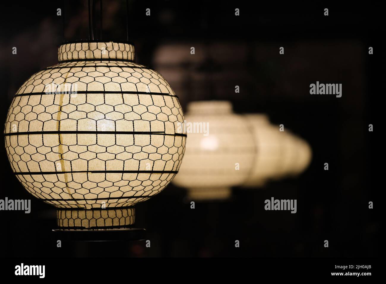 Lanternes chinoises traditionnelles dans une rangée dans la nuit sombre. Les lanternes asiatiques sont de moins en moins en perspective sur fond noir Banque D'Images