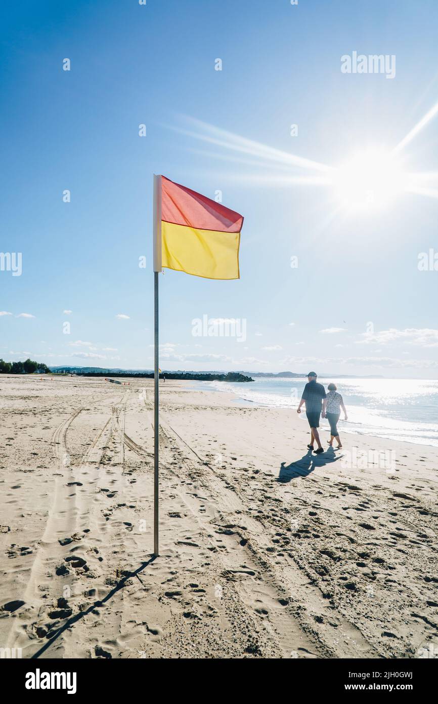 Couple marchant à côté du drapeau de Lifeguard sur la Gold Coast Banque D'Images