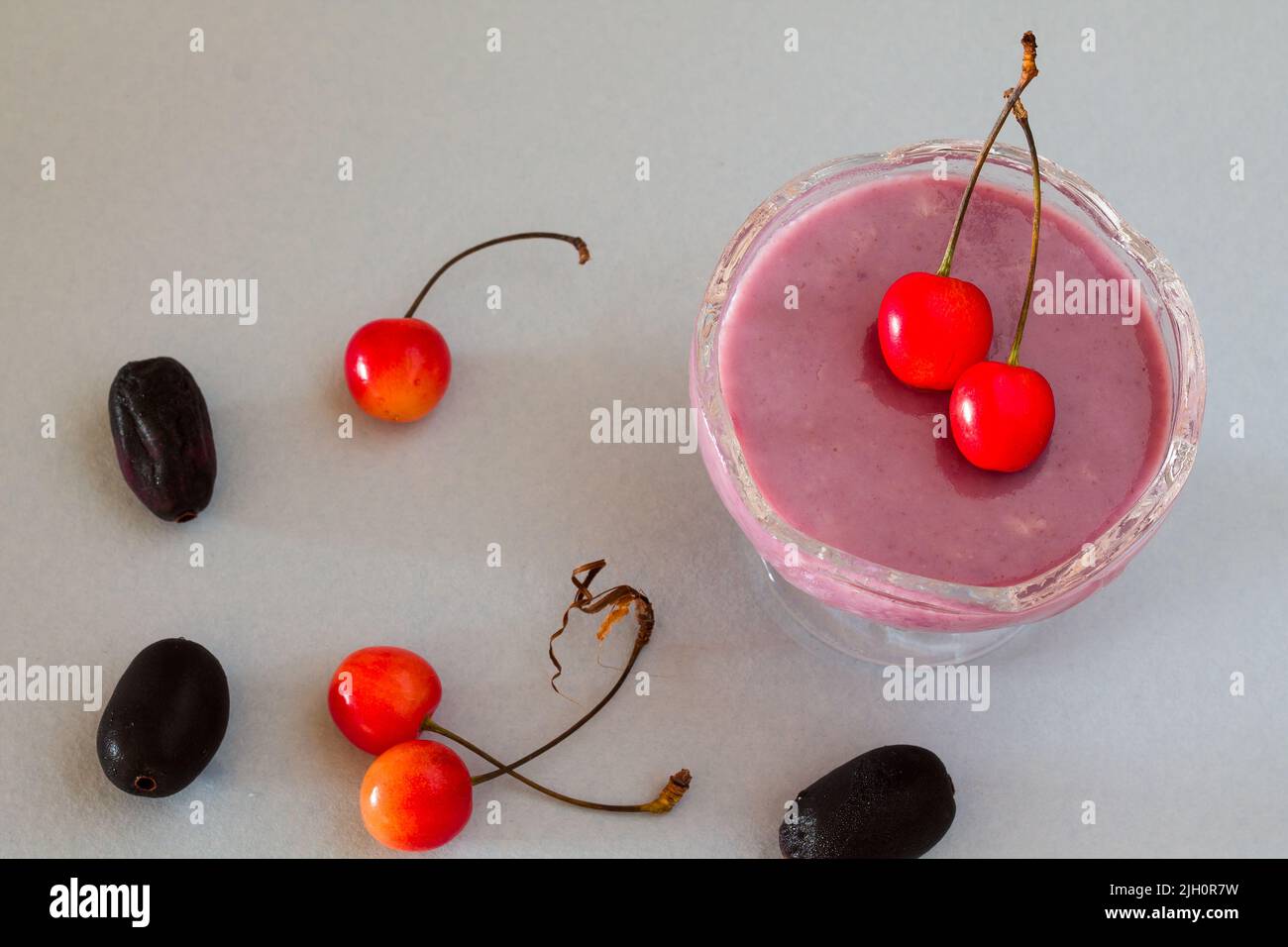 Gros plan, vue de dessus de Jamun Souffle, dessert traditionnel français d'été fait avec Jamun, surmonté de cerises et isolé sur fond gris clair. Banque D'Images