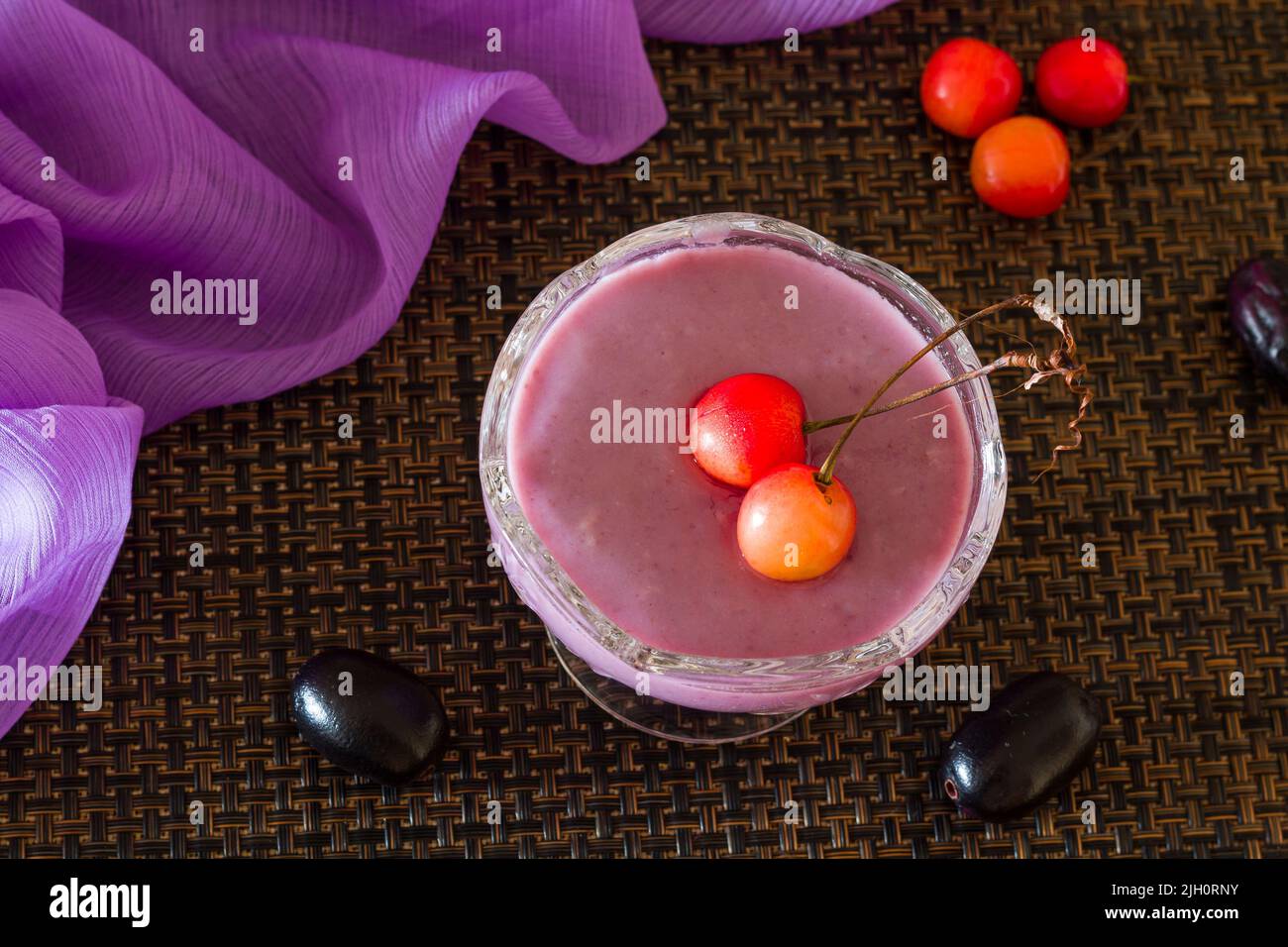 Mousse Jamun ou mousse Black Plum recouverte de cerises. Dessert vegan maison frais. Vue sur le dessus, gros plan du bol isolé sur fond sombre. Espace copie. Banque D'Images