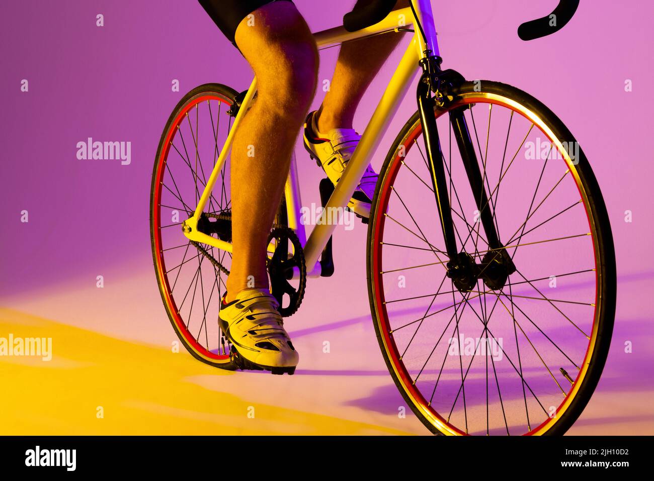 Cycliste caucasien avec vélo sur éclairage rose Banque D'Images