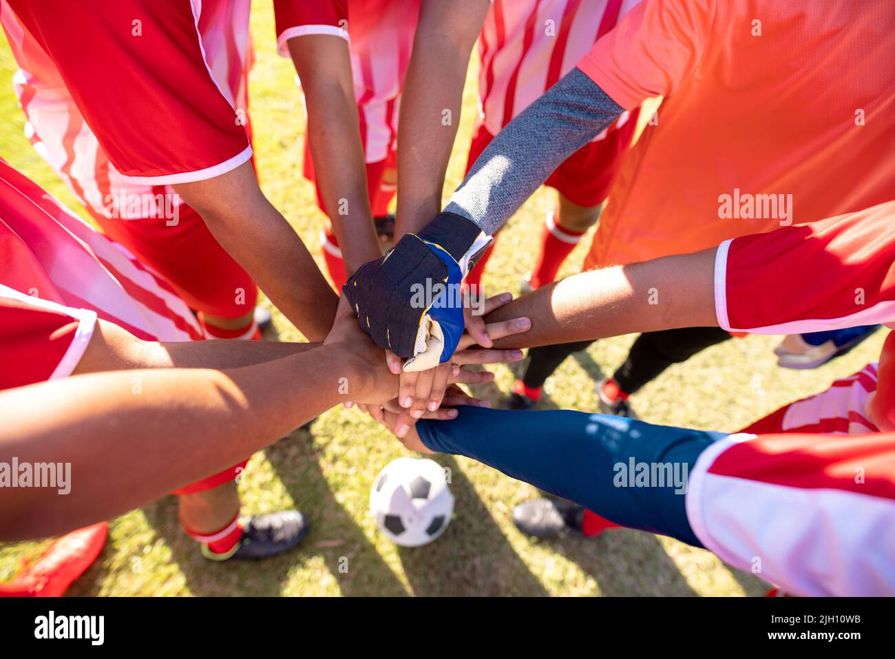 Vue en grand angle des joueurs de l'équipe de football multiracial masculins qui se empilent les mains avant le match sur le terrain de jeu Banque D'Images