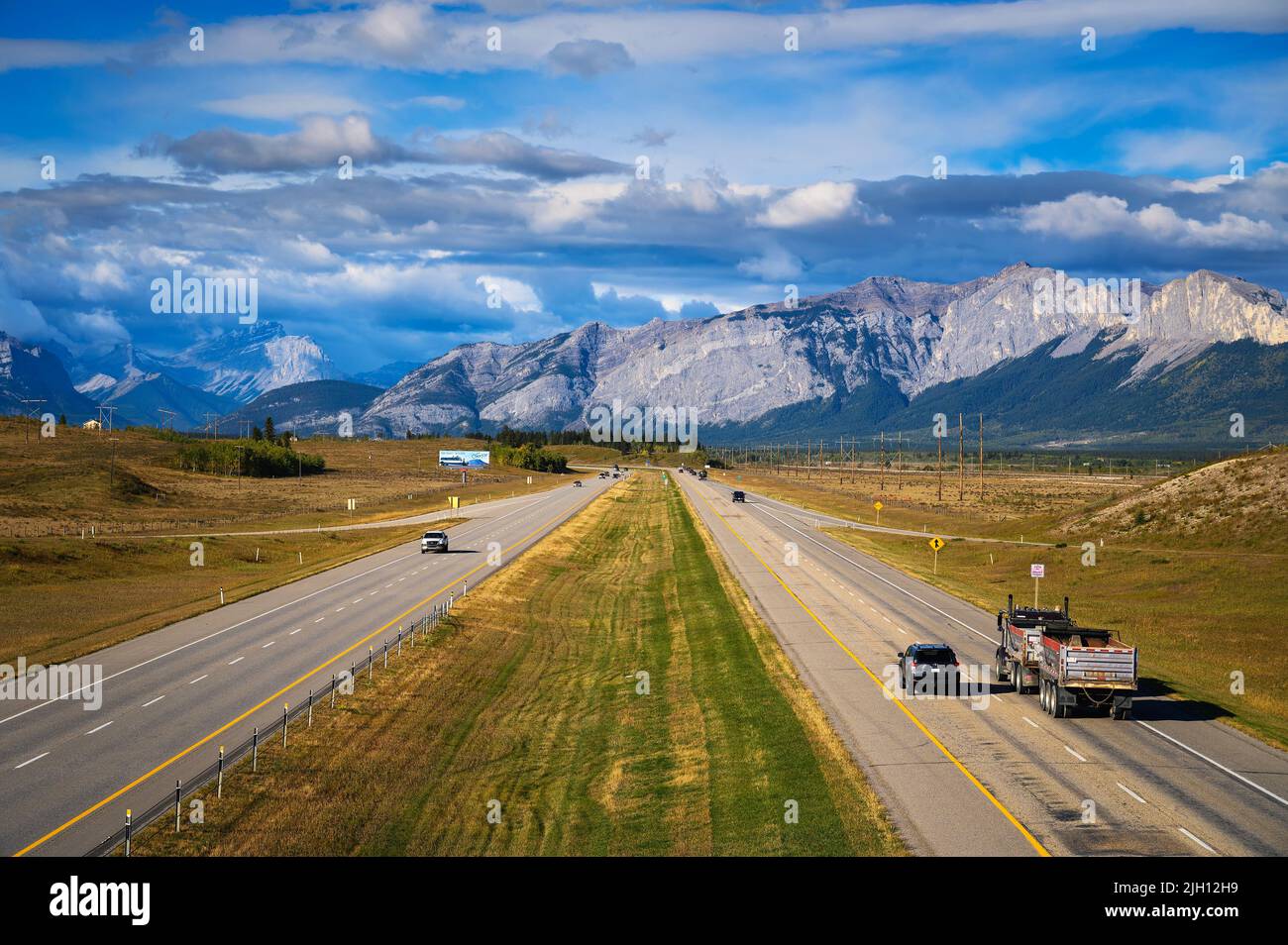 Les voitures se déplacent sur l'autoroute transcanadienne avec les montagnes Rocheuses canadiennes en arrière-plan Banque D'Images