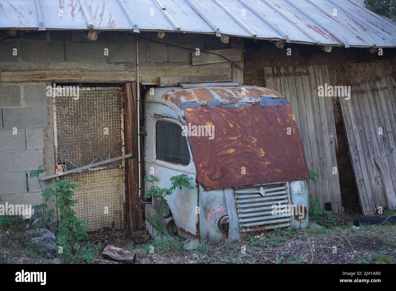 avant d'un vieux camion rouillé embarqué dans une ancienne maison en pierre en france Banque D'Images