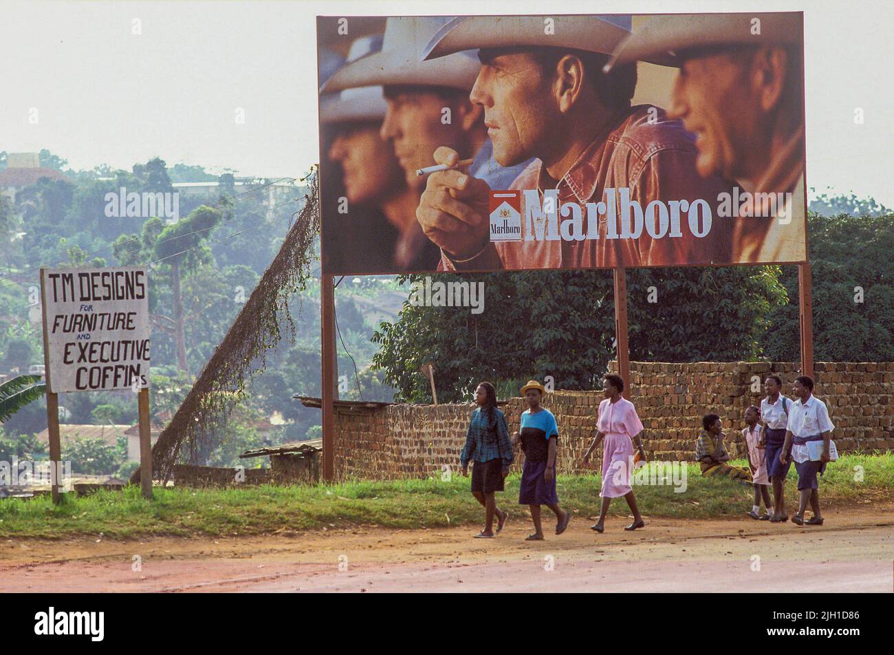 Ouganda, Kampala; scène de rue avec des gens passant un énorme panneau publicitaire publicité Marlboro sigarets. Banque D'Images