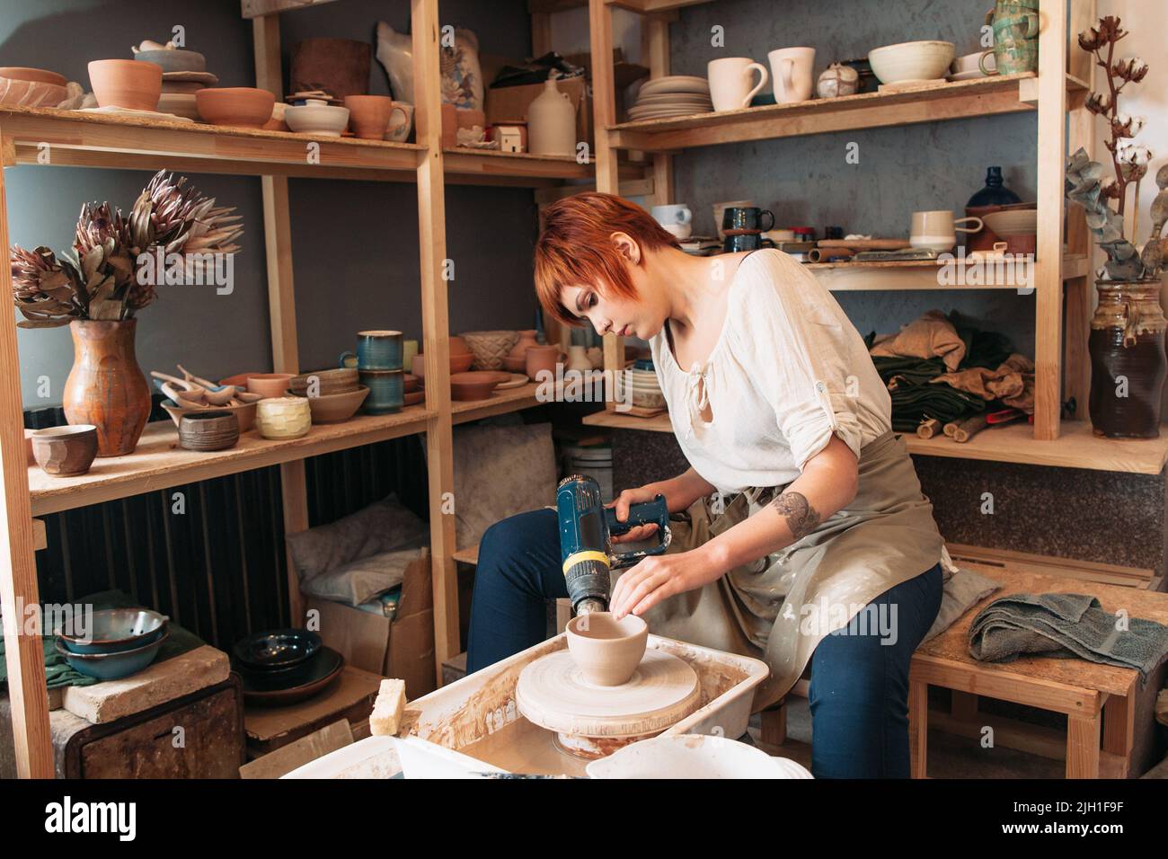 Séchage en poterie avec sèche-linge spécial. Jeune femme potier travaillant avec soin. Petite entreprise de femme Banque D'Images