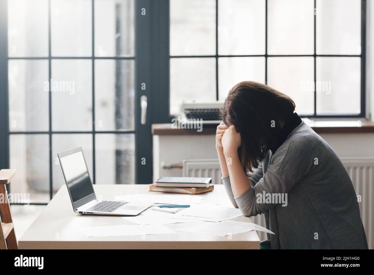 Femme entrepreneur assise au bureau et semble confondue avec un ordinateur portable sur le bureau. Problèmes d'affaires, crise, faillite concept Banque D'Images