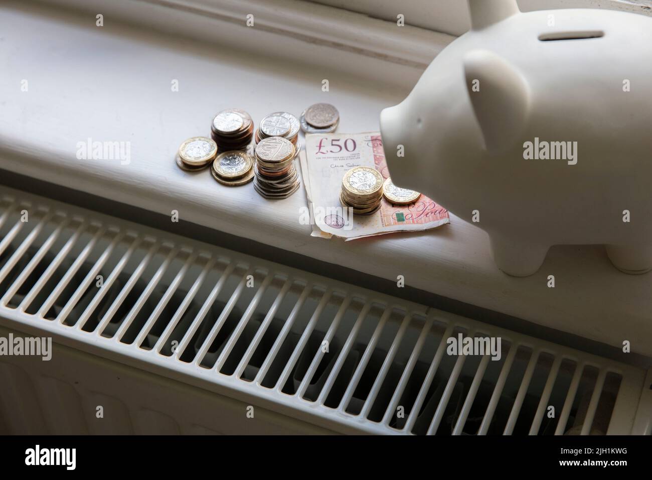 Crise du coût de la vie. De l'argent sur un radiateur de chauffage de maison. Augmentation du coût de l'énergie et des factures Banque D'Images