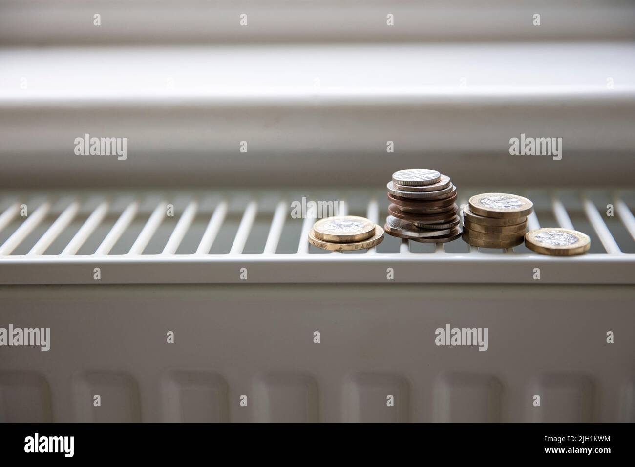 Crise du coût de la vie. De l'argent sur un radiateur de chauffage de maison. Augmentation du coût de l'énergie et des factures Banque D'Images