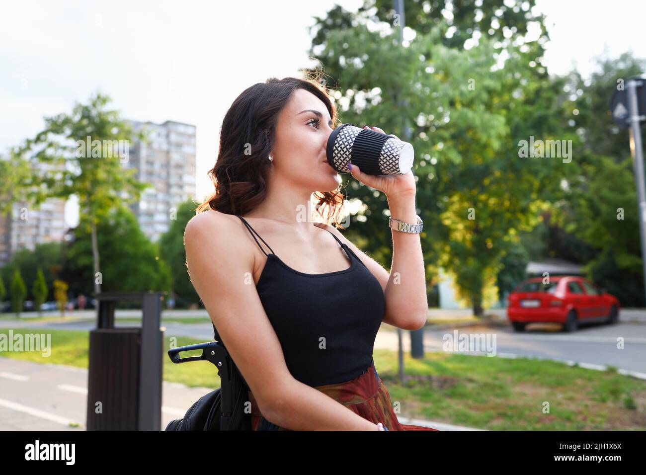 Une femme en fauteuil roulant ayant une pause-café dans un parc. Banque D'Images