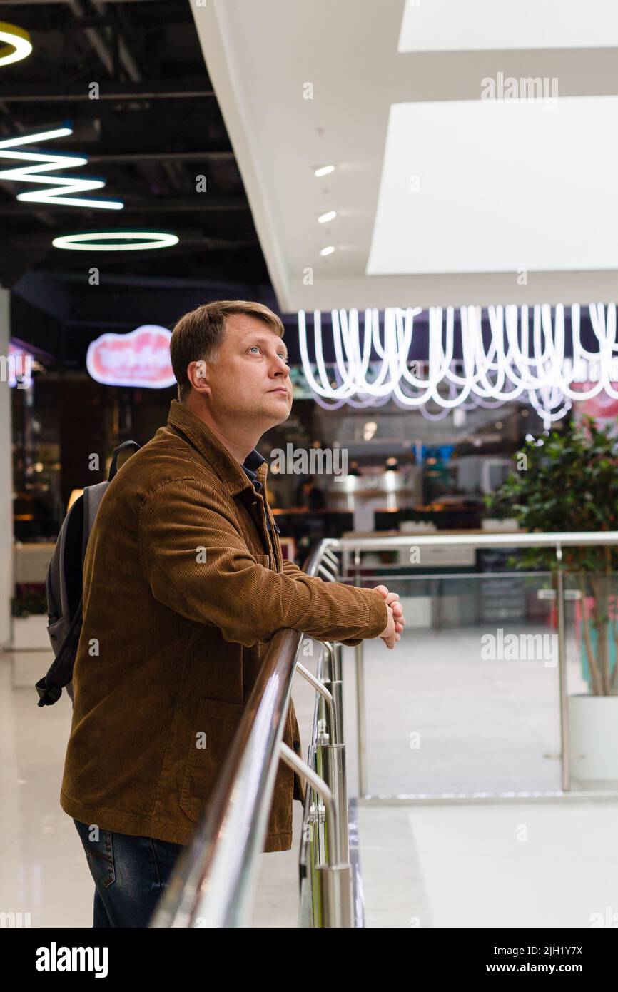 Un homme blond adulte dans une veste en velours côtelé attendant un ami au centre commercial. Banque D'Images