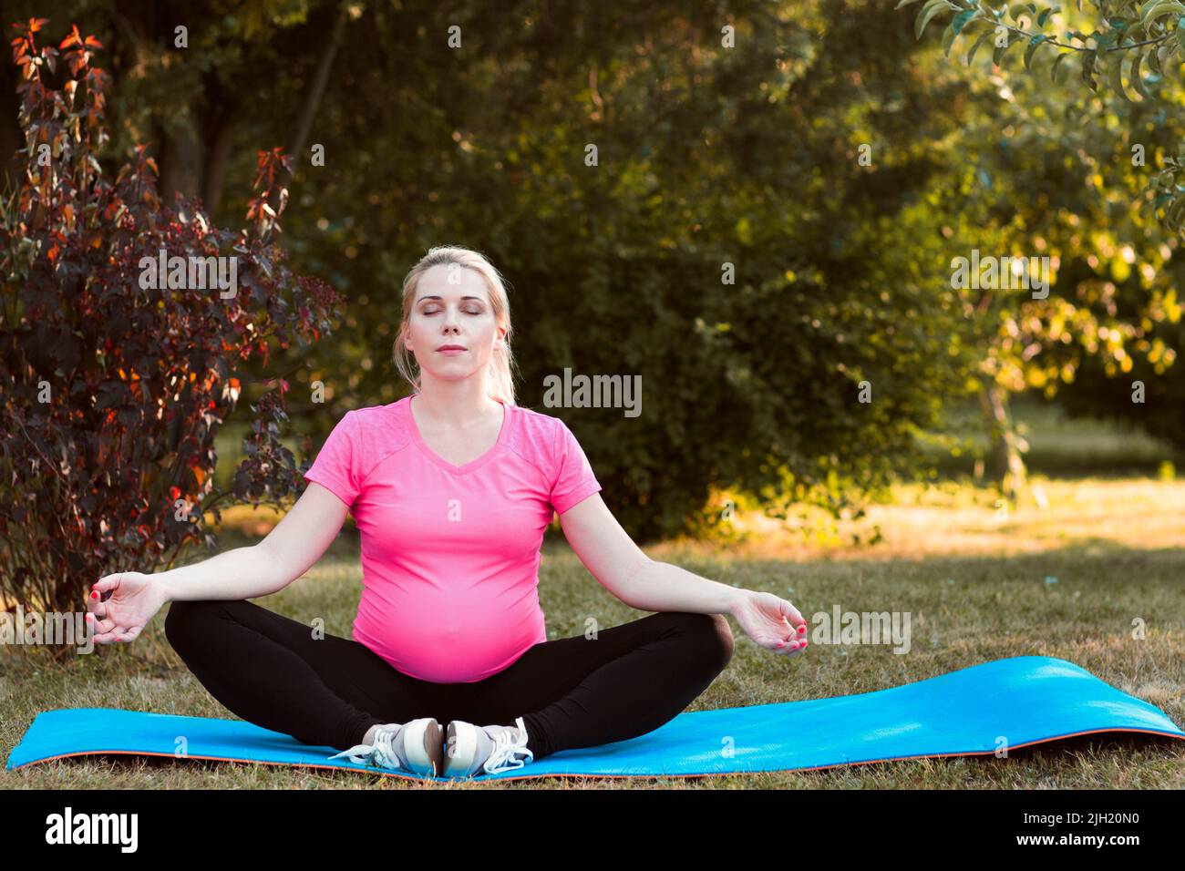 Jolie femme enceinte pratiquant le yoga en plein air Banque D'Images