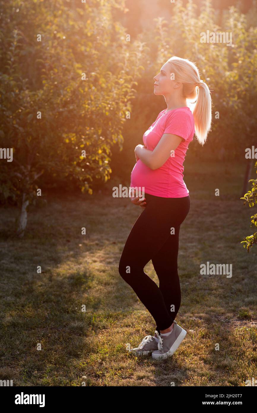 Femme enceinte au lever du soleil dans le jardin Banque D'Images