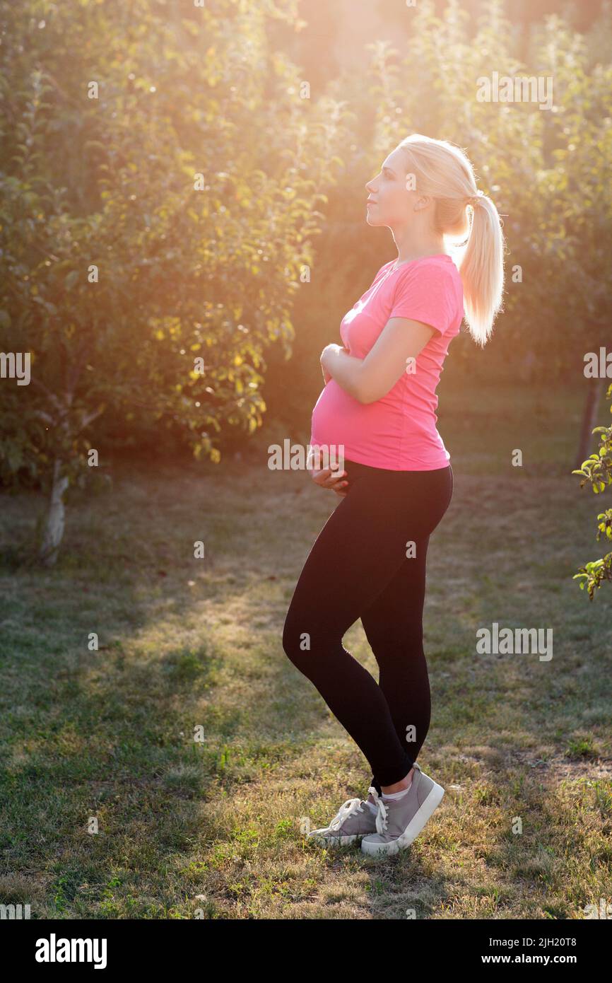 Femme enceinte au lever du soleil dans le jardin Banque D'Images