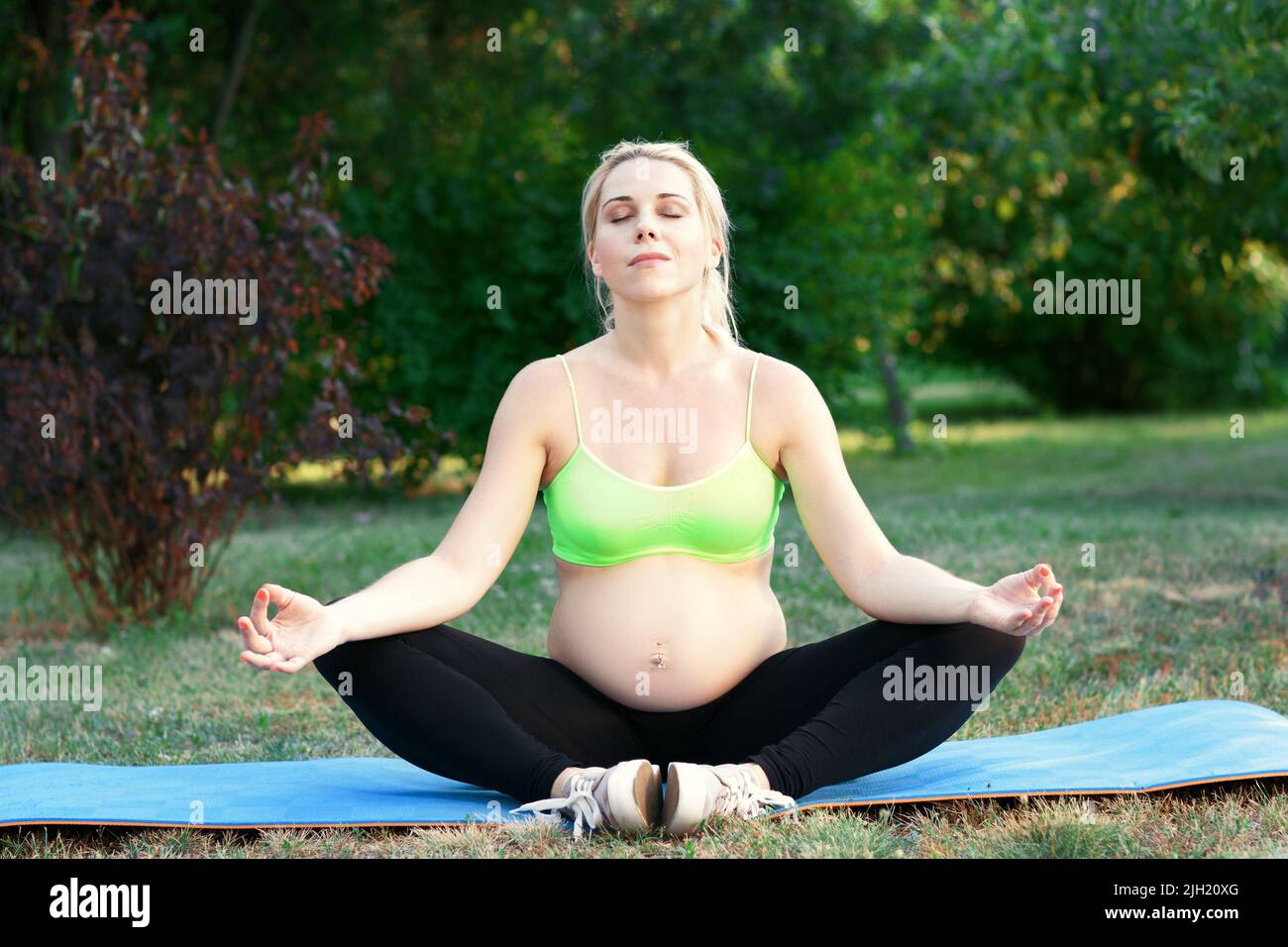 Femme enceinte méditant à l'extérieur Banque D'Images