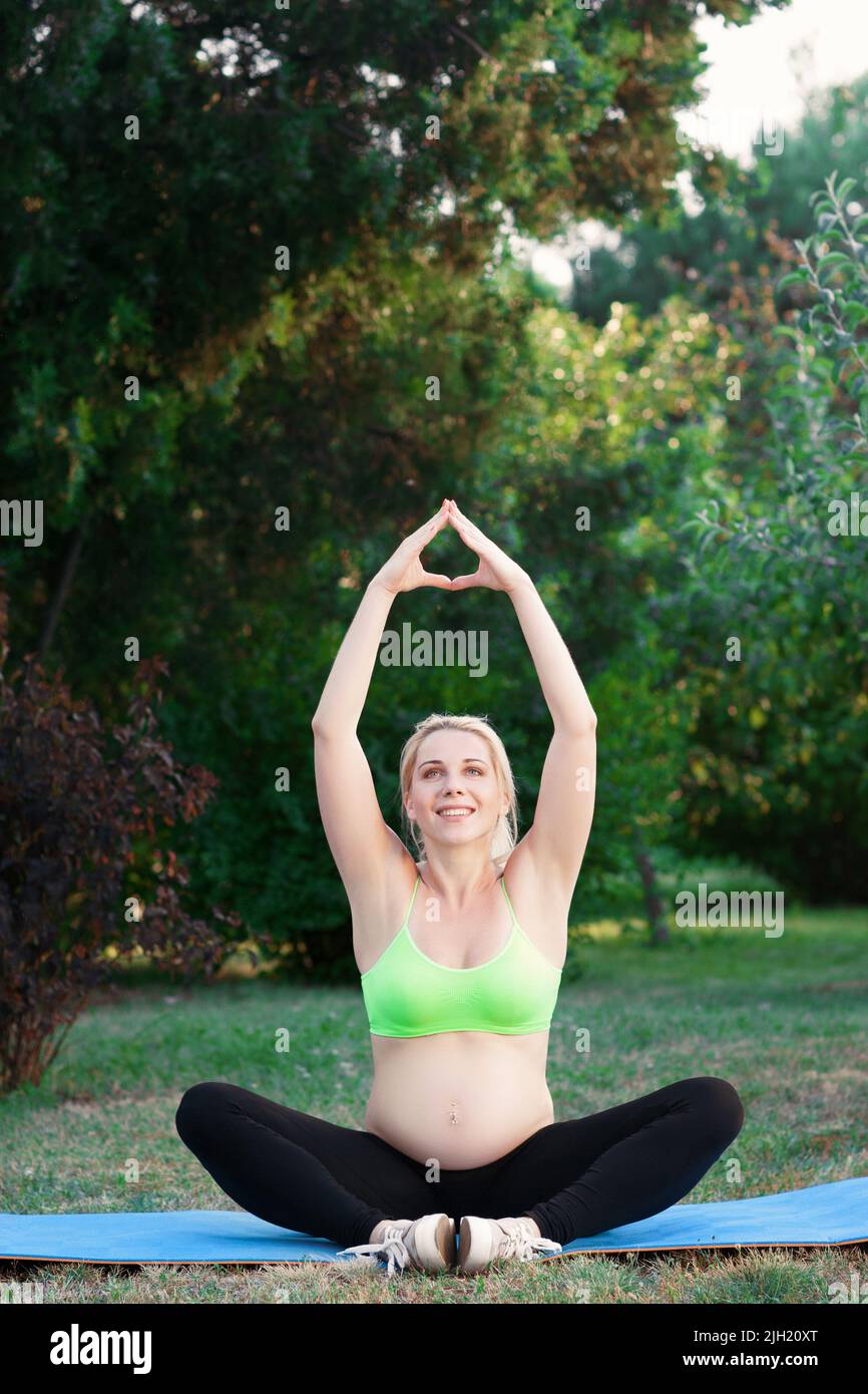 Grossesse souriante pratiquant le yoga dans la nature Banque D'Images