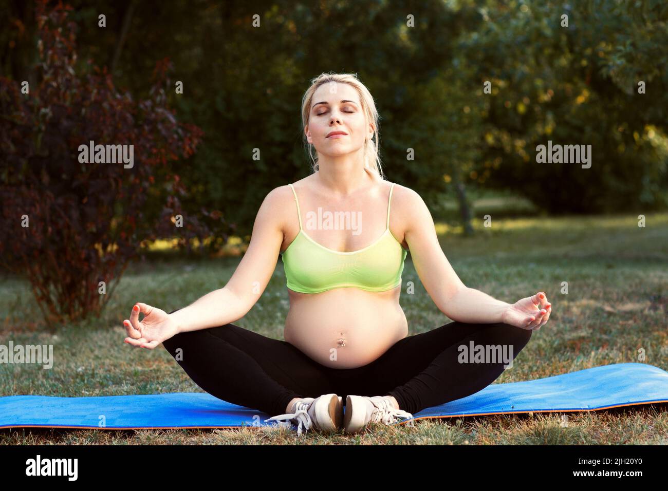 Femme enceinte méditant à l'extérieur Banque D'Images