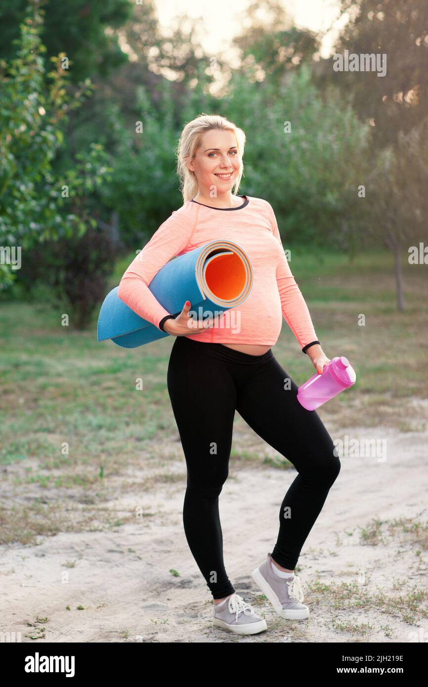 Femme enceinte souriante prête pour la remise en forme à l'extérieur Banque D'Images