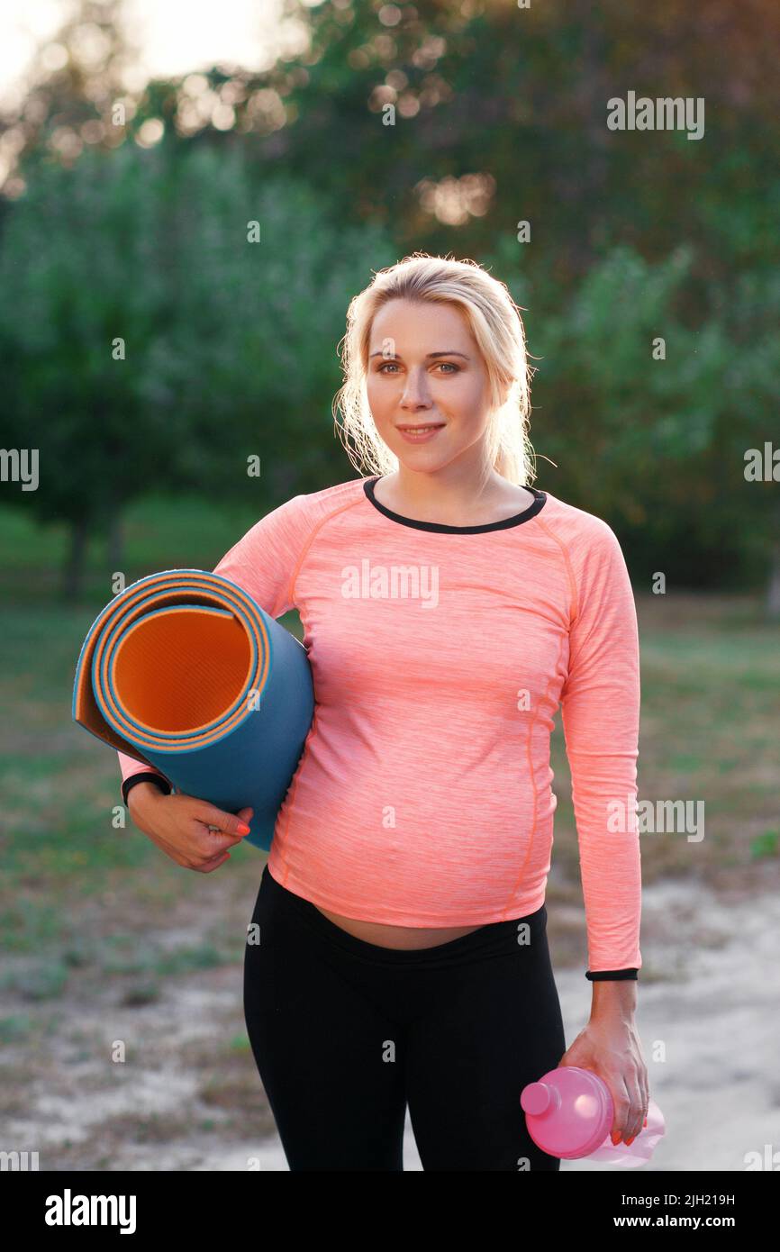 Femme de fitness enceinte souriant à l'appareil photo Banque D'Images