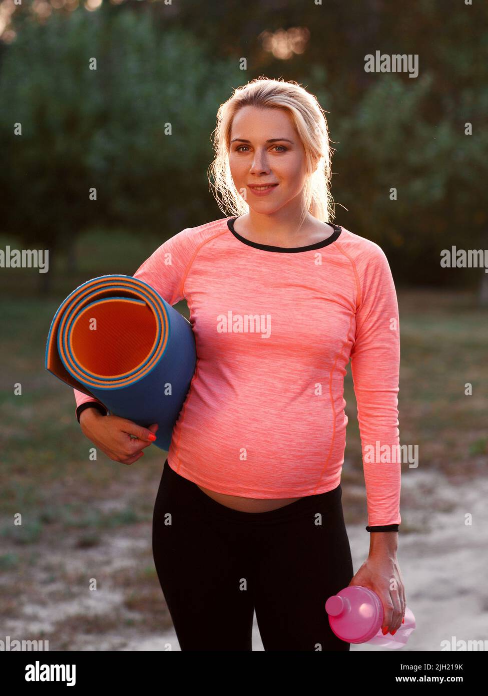 Femme de fitness enceinte souriant à l'appareil photo Banque D'Images