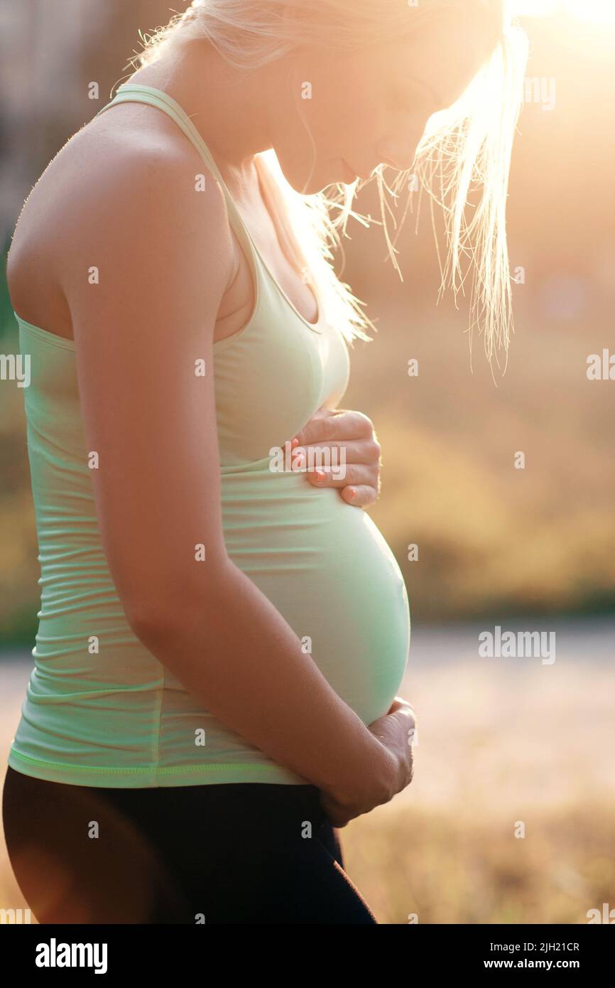 Profil de la femme enceinte embrassant son ventre Banque D'Images