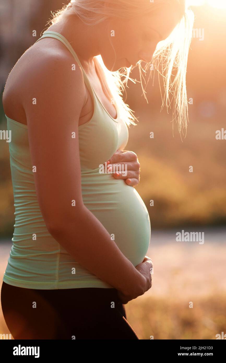Profil de la femme enceinte embrassant son ventre Banque D'Images